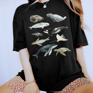 May include: A black t-shirt with a watercolor design of various sea creatures, including a seal, manatee, whale, dolphin, and a stingray.