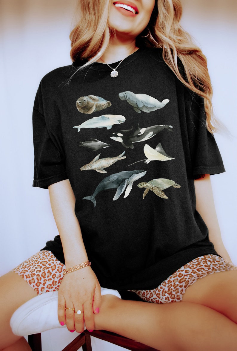May include: A black t-shirt with a watercolor design of various sea creatures, including a seal, manatee, whale, dolphin, and a stingray.