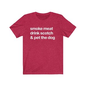 May include: Red short-sleeved t-shirt with white text that reads "smoke meat drink scotch & pet the dog"