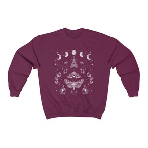May include: A maroon sweatshirt with a white graphic design featuring moths, mushrooms, and crescent moons.