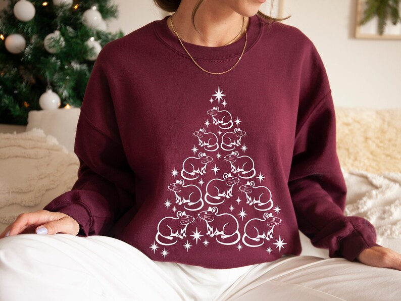 May include: A maroon sweatshirt with a white design of a Christmas tree made of rats. The rats are arranged in a pyramid shape, with the largest rat at the top and the smallest rats at the bottom.