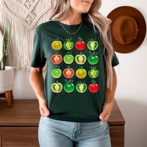 May include: A dark green t-shirt with a graphic print of a grid of tomatoes in various stages of ripeness, from green to red.