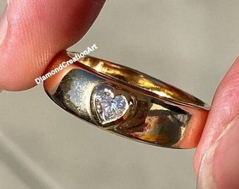 Op de afbeelding: Een gouden ring met een hartvormige diamant in het midden.