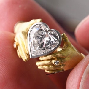 Ring with two hands holding a heart meaning hot sale