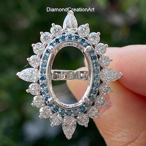 May include: Oval ring setting with a halo of round and pear-shaped diamonds and a border of blue diamonds.  DiamondCreationArt.