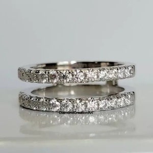 May include: A delicate, double-band ring with a sparkling row of small diamonds set in a silver band. The ring is designed to be worn as a wedding band or a promise ring.