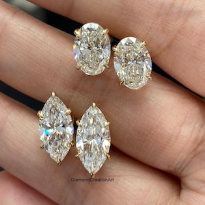 Op de afbeelding: Twee paar diamanten oorstekers. Eén paar heeft ovaal geslepen diamanten en het andere paar heeft peervormige diamanten. Beide sets zijn gezet in gouden klauwen, die de schittering van de edelstenen benadrukken. De oorbellen worden op een neutrale achtergrond gepresenteerd.