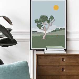 May include: A framed illustration of a stylized tree with a yellow sun in a blue sky. The tree is brown with green leaves and is set against a green grassy field with hills in the background.