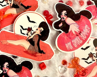 May include: Four colorful stickers featuring a witch character in a variety of poses. The stickers are on a white background with red and white candy hearts and other decorative elements. The text on one sticker reads "Hot Ghoul Summer".