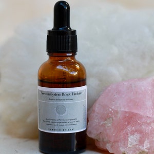 May include: A brown glass bottle with a black dropper top. The bottle is labeled "Nervous System Reset Tincture -  Revisi&oacute;n del sistema nervioso -  A direct modulation of PNS Neurotransmitter for  N.A.D. that relieves symptoms such as insomnia, anxiety, depression, mood imbalance, worry and stress. Essence of Zasi"