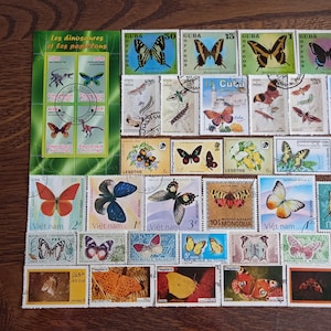 Può includere: Una collezione di francobolli raffiguranti varie specie di farfalle e falene provenienti da paesi come Cuba, Vietnam e Mongolia. Un foglio verde intitolato Les dinosaures et les papillons mostra quattro piccole illustrazioni di dinosauri.