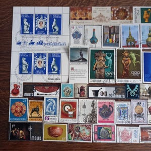 May include: A collection of various postage stamps featuring diverse imagery including portraits of Queen Elizabeth II, historical artifacts, Olympic themes, and cultural icons from countries like South Georgia, Malta, and Spain.