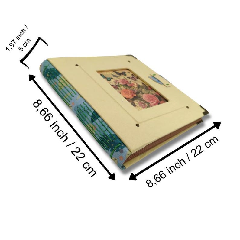 May include: A beige photo album with a floral design in the center and a blue patterned spine. The album measures 8.66 inches (22 cm) long and wide, and 1.97 inches (5 cm) thick.