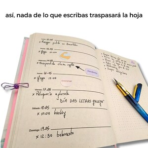 Puede incluir: Un cuaderno abierto con notas manuscritas y un clip morado. Las p&aacute;ginas del cuaderno est&aacute;n llenas de horarios diarios y listas de tareas. Un bol&iacute;grafo azul y dorado descansa en la p&aacute;gina derecha. El texto "D&Iacute;A DAS LETRAS GALEGAS" es visible.