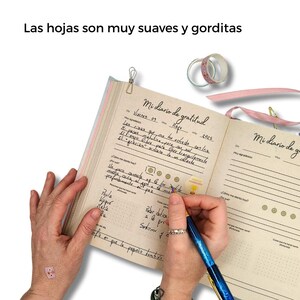 Puede incluir: Una taza de cer&aacute;mica blanca con asa negra y el texto "But First, Coffee" en negrita negra. La taza se encuentra sobre un fondo borroso, sugiriendo un ambiente acogedor.