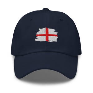 Peut inclure: Casquette de baseball bleu marine avec un drapeau anglais brodé. Le drapeau présente une croix rouge sur fond blanc, avec un effet de coup de pinceau vieilli. La casquette a une visière incurvée et une sangle réglable.
