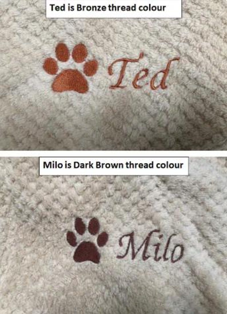 May include: A beige textured fabric featuring two embroidered designs. The top section shows a bronze paw print and the name Ted. The bottom section displays a dark brown paw print and the name Milo, with text labels indicating the thread colors.