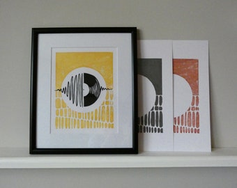 May include: Three framed prints with a black and white graphic of a record with sound waves. The prints are on yellow, gray, and orange backgrounds.