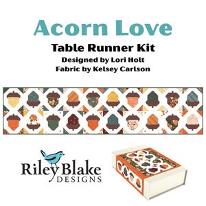 May include: Acorn Love Table Runner Kit designed by Lori Holt with fabric by Kelsey Carlson. The kit includes a rectangular box and a long table runner featuring a repeating pattern of brown-capped acorns in various orange, green, and floral prints.
