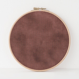 May include: A brown embroidery hoop with brown fabric stretched across the frame.