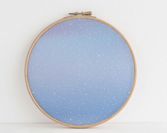 Puede incluir: Un aro de bordado redondo con un fondo degradado azul y morado y puntos blancos, que se asemeja a un cielo estrellado.