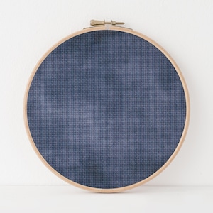 Puede incluir: Un aro de bordado redondo con una tela azul oscuro estirada sobre el marco.