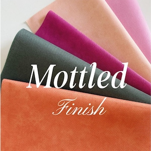 May include: A collection of fabric swatches in various colors, including orange, dark green, fuchsia, peach, and pink. The fabric has a mottled finish, with the words "Mottled Finish" in white script across the image.