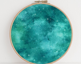 Puede incluir: Una pintura de acuarela azul verdosa de un cielo nocturno estrellado en un aro de bordado de madera.