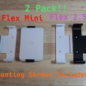 May include: Two white wall mounts for a phone or tablet, with the text "Flex Mini" and "Flex 2.5G" above them.  The mounts are made of plastic and have a white finish.  The text "Mounting Screws Included" is below the mounts.