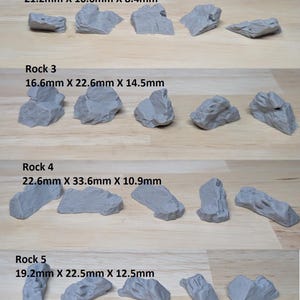 May include: A collection of 30 miniature rocks in various shapes and sizes, each a light grey colour. The largest rock measures 22.6mm x 33.6mm x 10.9mm. The text "30pc Rock Bundle" is at the top of the image.