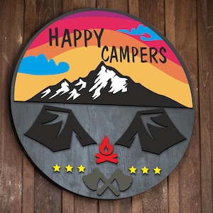 May include: A round wooden sign with the text "HAPPY CAMPERS" in a rainbow arc over a black silhouette of a mountain with snow on the peak. Below the mountain are two black silhouettes of tents with a red campfire between them. There are five yellow stars and two crossed black axes below the tents.