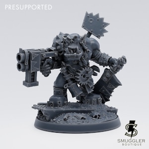 Könnte beinhalten: Eine graue Plastikminiatur eines Orks mit einer großen Waffe und einer Powerkralle. Die Miniatur steht auf einer Base mit einem Metallgitter und Trümmern. Die Miniatur ist vormontiert.