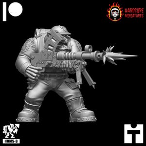 May include: A grey plastic miniature of an Orc soldier holding a large, detailed, futuristic weapon with a spiked barrel. The Orc is wearing a helmet and a uniform with a patch that says "T".