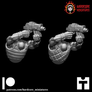 May include: Two gray 3D printed miniature figures holding futuristic weapons. The figures are wearing armor and have detailed facial features.