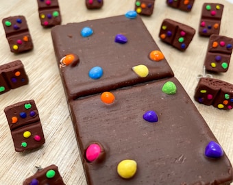 May include: A set of 12 chocolate bar earrings with colorful sprinkles. The earrings are made of polymer clay and are perfect for adding a touch of whimsy to any outfit.