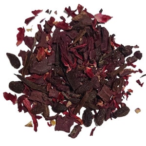 May include: A close-up of a pile of dried hibiscus flowers and other herbs, including dark brown pieces and small black seeds. The mixture is a deep red colour.