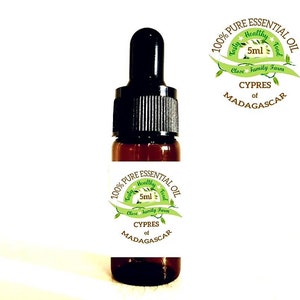 Peut inclure: Une bouteille en verre ambré de 5 ml d'huile essentielle de Cyprès de Madagascar. La bouteille est munie d'un compte-gouttes et d'une étiquette blanche avec du texte vert qui indique "100% Pure Huile Essentielle Délicieux Sain Nourriture Ferme Familiale Proche Cyprès de Madagascar".