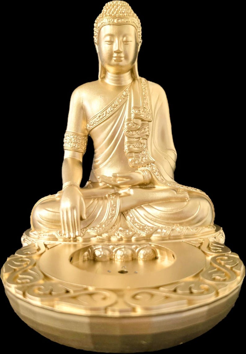 K&ouml;nnte beinhalten: Eine goldene Buddha-Statue in sitzender Meditationshaltung, vor schwarzem Hintergrund. Die Statue weist aufwendige Details in ihren Gew&auml;ndern und Verzierungen auf. Der Sockel hat ein dekoratives Design.