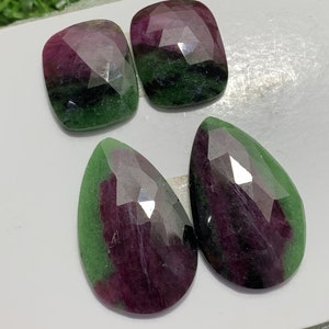 Könnte beinhalten: Vier grüne, rosafarbene und schwarze Edelsteine. Zwei sind quadratisch und zwei sind tropfenförmig.