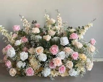 May include: A dense floral display with roses in pink, white, and cream hues. The arrangement includes baby's breath and other foliage, creating a full, textured appearance. Ideal for weddings or special occasions. The arrangement is a beautiful display of flowers.