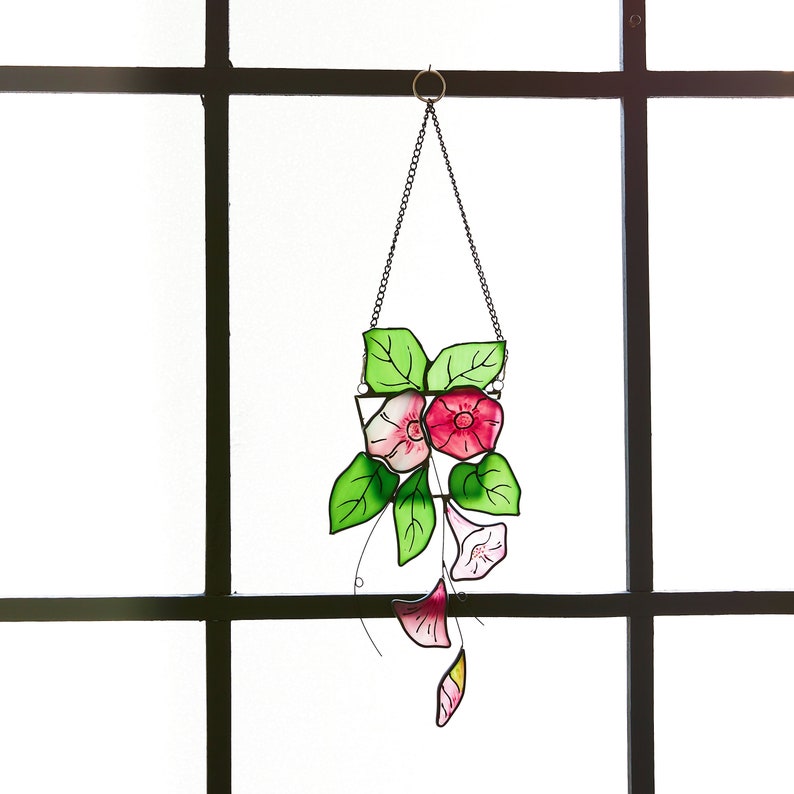 Peut inclure: Une suspension en verre color&eacute; repr&eacute;sentant une fleur rose et blanche avec des feuilles vertes dans un pot blanc. La suspension est suspendue &agrave; une cha&icirc;ne argent&eacute;e.