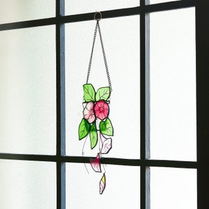 Peut inclure: Une suspension en verre color&eacute; repr&eacute;sentant des fleurs roses et blanches avec des feuilles vertes. Les fleurs ont la forme de liserons. La suspension est suspendue &agrave; une cha&icirc;ne.