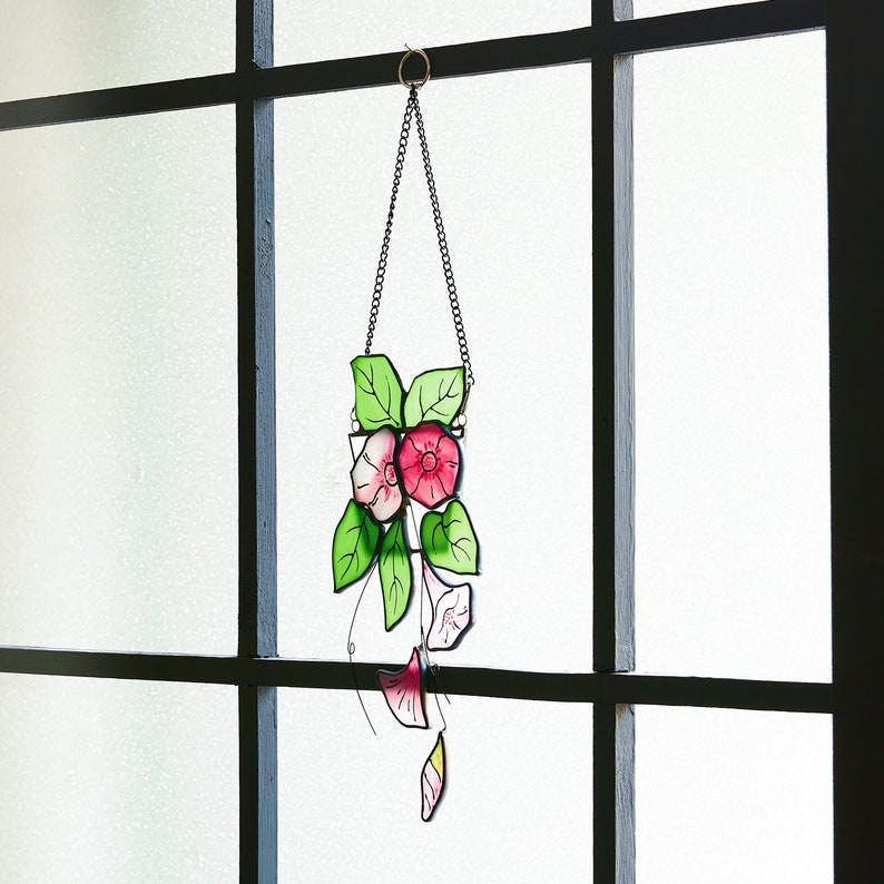 Peut inclure: Une suspension en verre color&eacute; repr&eacute;sentant des fleurs roses et blanches avec des feuilles vertes. Les fleurs ont la forme de liserons. La suspension est suspendue &agrave; une cha&icirc;ne.