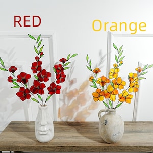 May include: Two vases of artificial flowers on a wooden table. One vase holds red flowers, the other holds orange flowers. The text "RED" and "Orange" are above the vases. The vases have a face design.