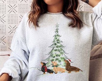May include: A gray sweatshirt with a Christmas tree and three dachshunds wearing Santa hats printed on the front.