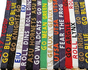 May include: A collection of 16 beaded straps with various college and university logos and slogans, including "Go Blue", "Go Knights", "EIU Panthers", "Roll Dins", "ASU Hornets", "Go Wildcats", "Go Mean Green", "Geaux Geaux", "UTSA", "Fear the Frog", "Go Argyle", "Roll Lynx", "Go Irish", and "Go Blue". Each strap has a gold metal clasp.