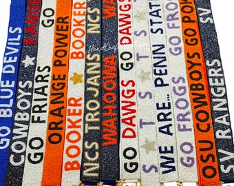 May include: A collection of beaded straps with various college team names and logos, including "Go Blue Devils", "Cowboys", "Go Friars", "Orange Power", "Booker", "NCS Trojans", "Wahooma", "Go Dawgs", "SATS", "We Are Penn State", "Go Frogs", "OSU Cowboys", and "SV Rangers".