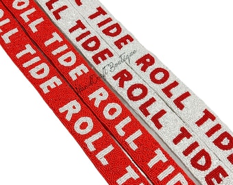 May include: Two beaded trim strips with the words "Roll Tide" repeated in white beads on a red background and red beads on a white background.