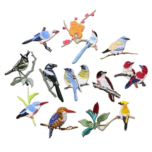 Könnte beinhalten: Eine Sammlung gestickter Vogelaufnäher in verschiedenen Farben, darunter Blau, Rot, Gelb und Grün. Jeder Aufnäher zeigt eine andere Vogelart, die auf einem Ast sitzt. Die Aufnäher sind zum Aufnähen oder Aufbügeln auf Stoff gedacht.