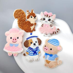 May include: Embroidered patches featuring a squirrel, cat, pig, dog, and another pig. The squirrel is brown, the cat is pink and white, and the pigs are pink and tan. The dog wears a sailor outfit. The patches are colorful and detailed.